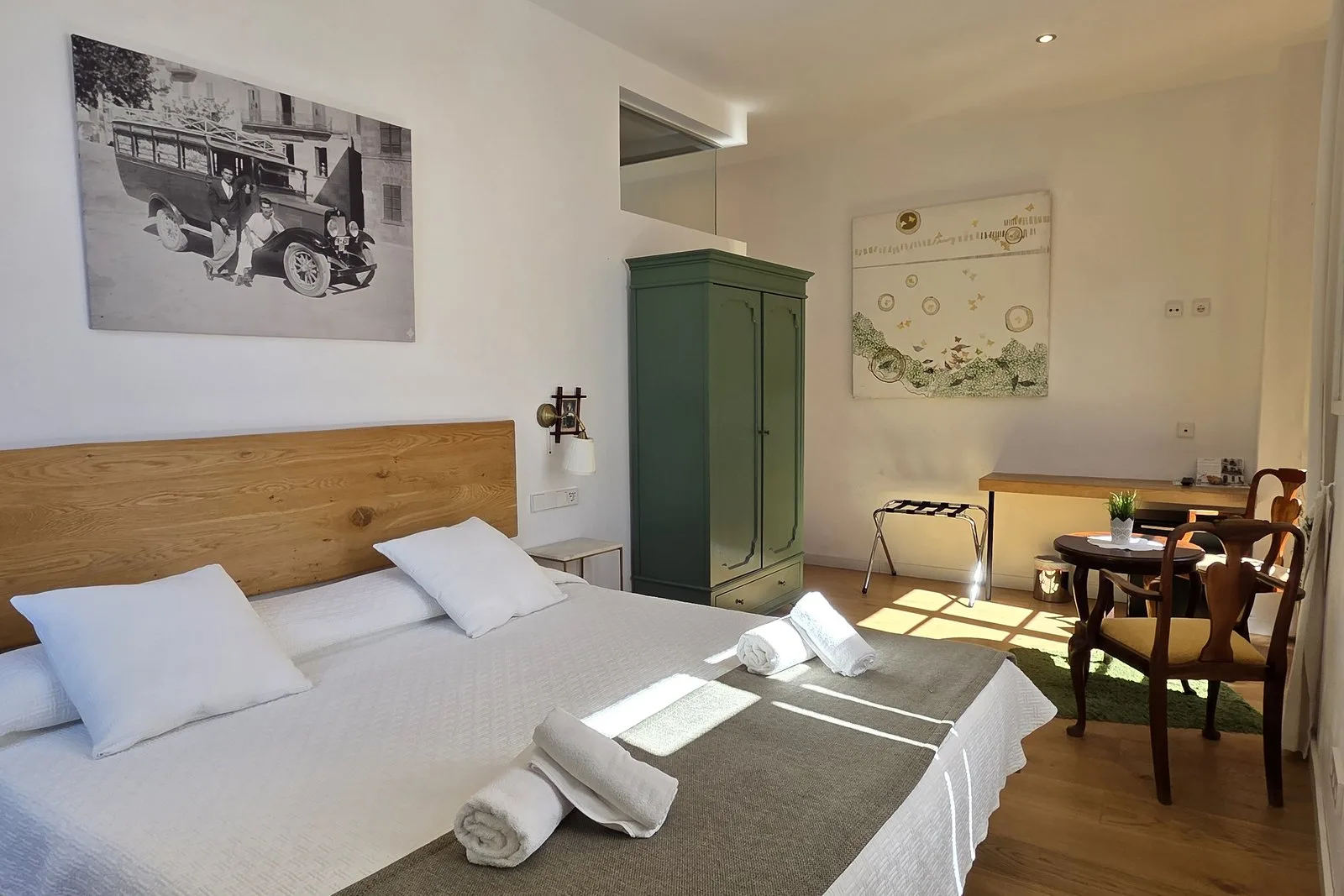 Habitación doble superior del Hotel Juma: cama, armario verde y mesa junto a la ventana